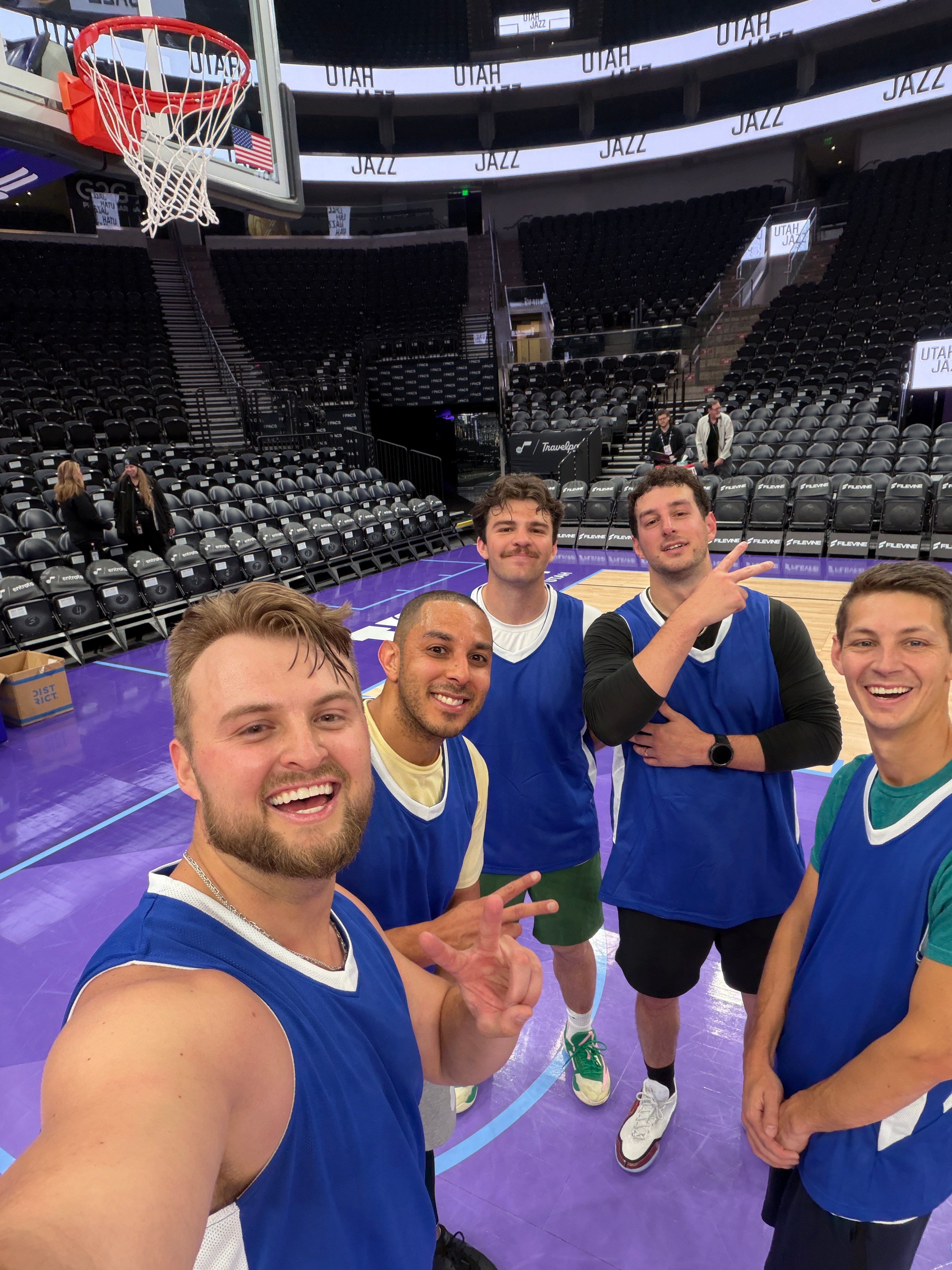 Friends in basketball jerseys on the Utah Jazz arena court